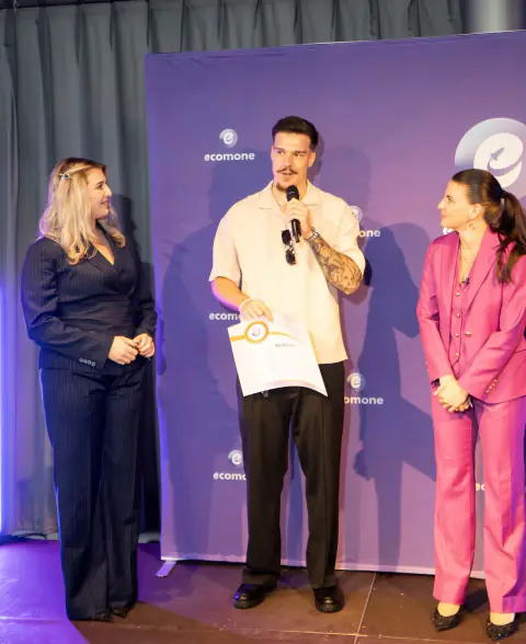 Amir hält auf der Ecomone-Bühne Zertifikat und Mikrofon.